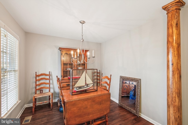 dining room with decorative columns, dark wood-type flooring, and an inviting chandelier