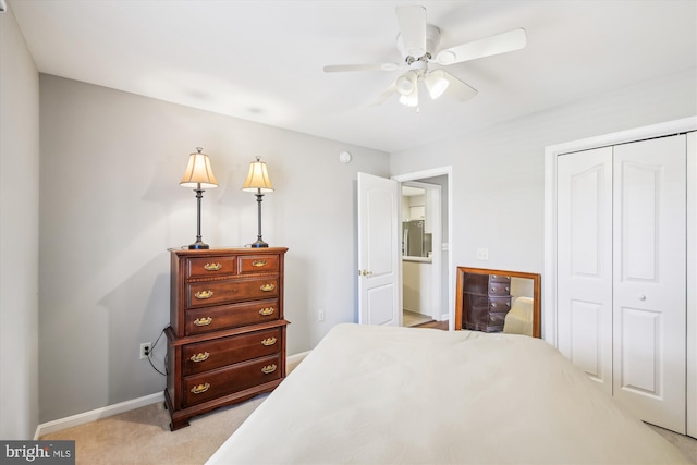 bedroom featuring light carpet, stainless steel fridge, ceiling fan, and a closet