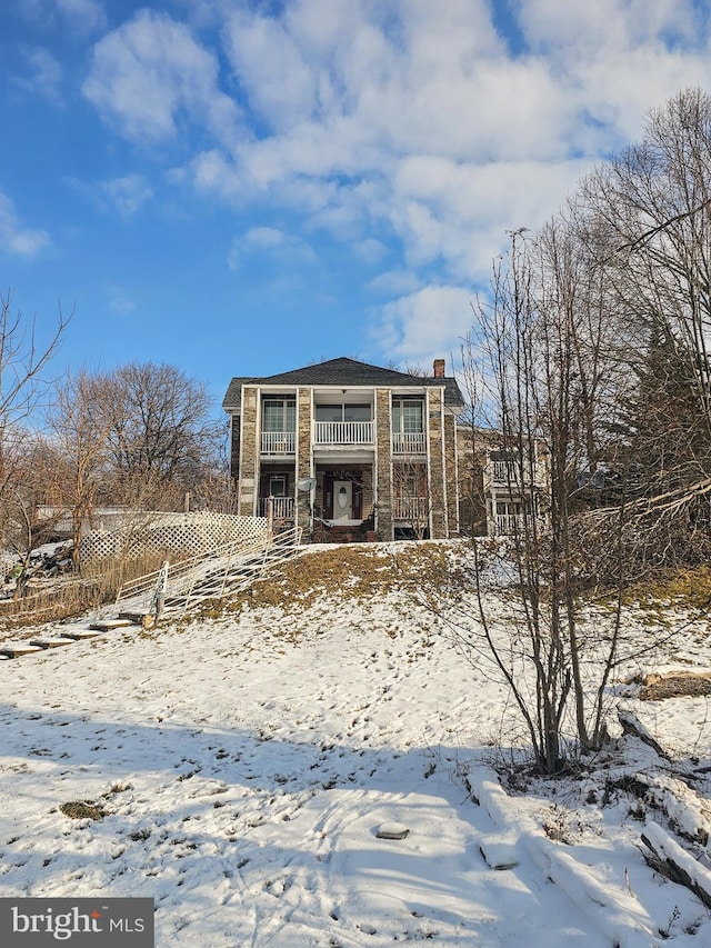 snow covered back of property with a balcony