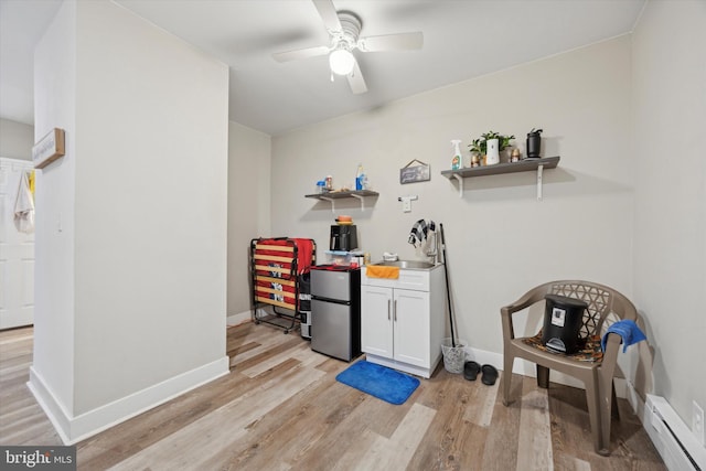 bar featuring white cabinetry, sink, ceiling fan, baseboard heating, and light hardwood / wood-style flooring