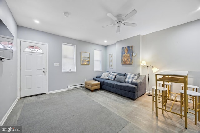 living room with ceiling fan, a baseboard radiator, a healthy amount of sunlight, and light wood-type flooring