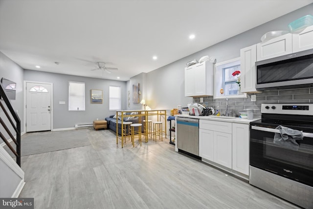 kitchen featuring sink, backsplash, stainless steel appliances, light hardwood / wood-style floors, and white cabinets