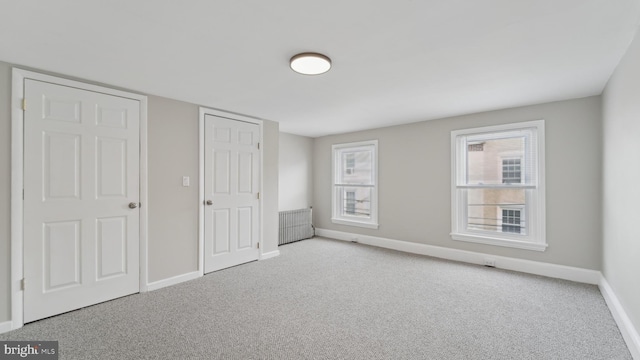 unfurnished bedroom featuring radiator and light carpet