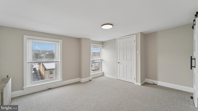 carpeted empty room featuring a barn door and radiator