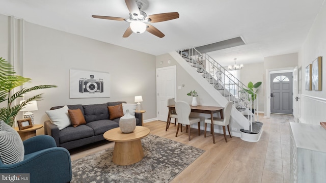 living room with ceiling fan with notable chandelier and light wood-type flooring