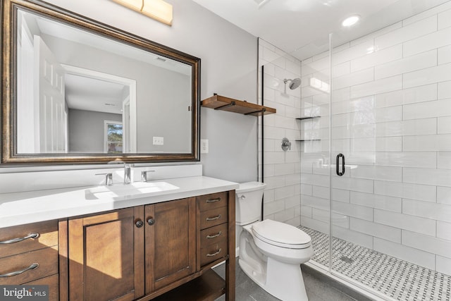 bathroom featuring toilet, vanity, and a shower with shower door