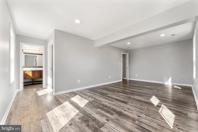 interior space with dark wood-type flooring and beam ceiling