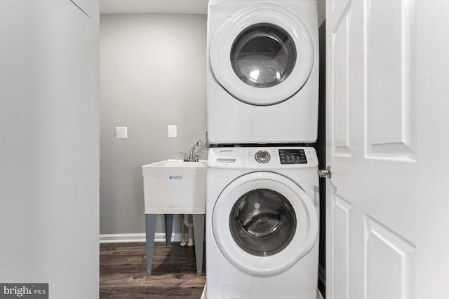 laundry room with stacked washer and dryer and dark hardwood / wood-style flooring