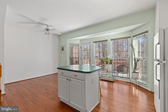 kitchen featuring white cabinetry, wood-type flooring, plenty of natural light, and white fridge