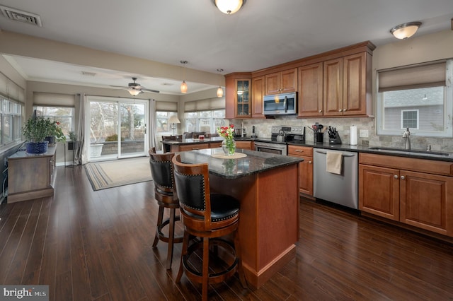 kitchen featuring sink, appliances with stainless steel finishes, tasteful backsplash, a kitchen island, and dark hardwood / wood-style flooring