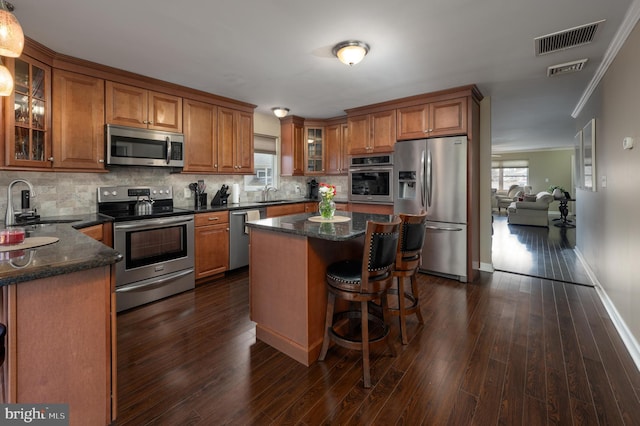 kitchen with stainless steel appliances, tasteful backsplash, a kitchen island, and sink