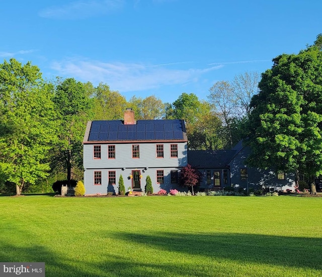 colonial inspired home with a front lawn and solar panels