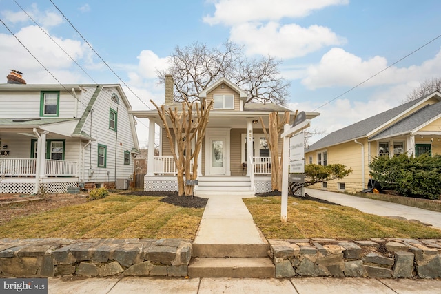 bungalow featuring central AC unit, a front lawn, and covered porch