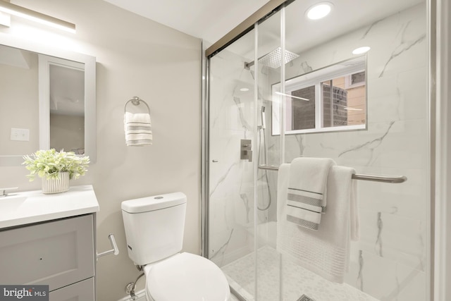 bathroom with vanity, a shower with door, and toilet