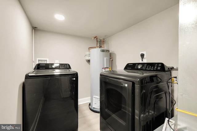 laundry room featuring water heater, washer and dryer, and light hardwood / wood-style floors