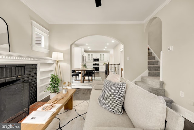 living room with a brick fireplace, light hardwood / wood-style flooring, and ornamental molding