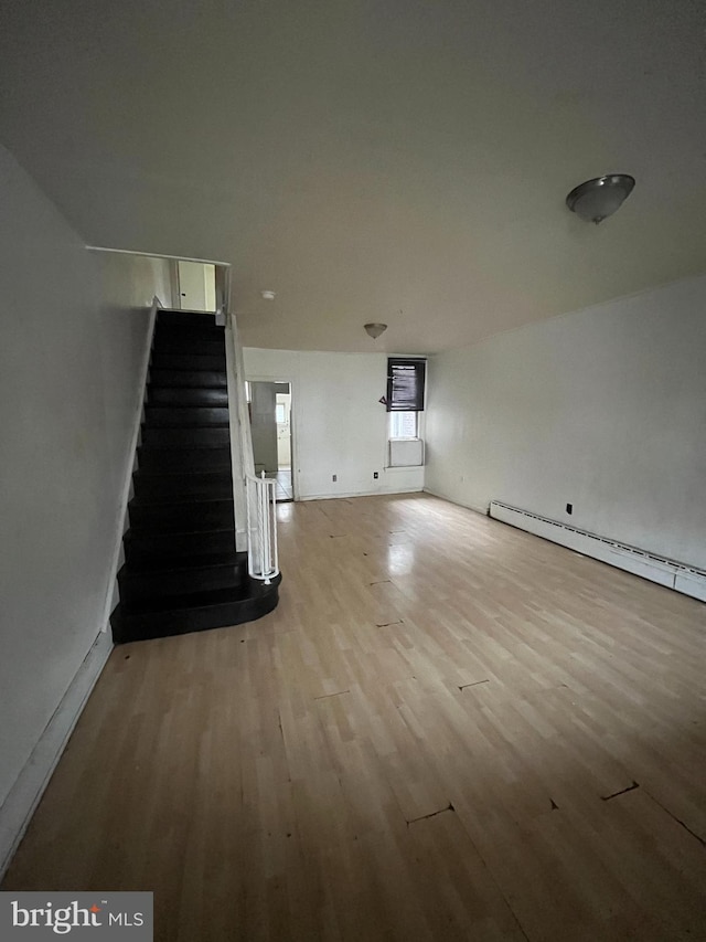 unfurnished living room featuring a baseboard heating unit and light wood-type flooring