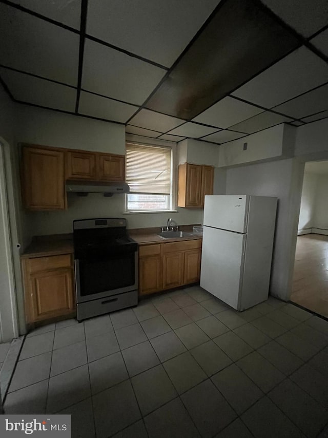 kitchen featuring light tile patterned flooring, a paneled ceiling, sink, stainless steel range with electric cooktop, and white refrigerator