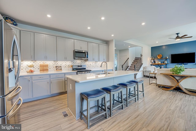 kitchen with tasteful backsplash, sink, a breakfast bar area, a kitchen island with sink, and stainless steel appliances