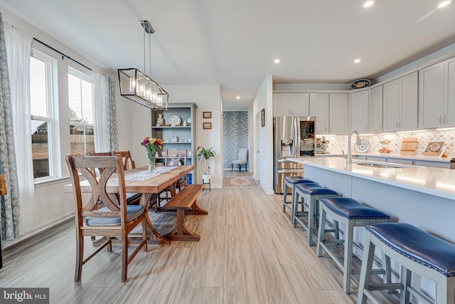 dining area featuring a notable chandelier, sink, and light wood-type flooring