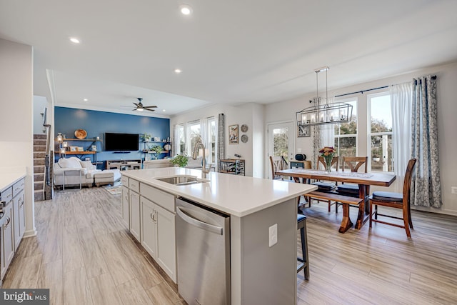 kitchen with sink, white cabinets, hanging light fixtures, a kitchen island with sink, and stainless steel dishwasher