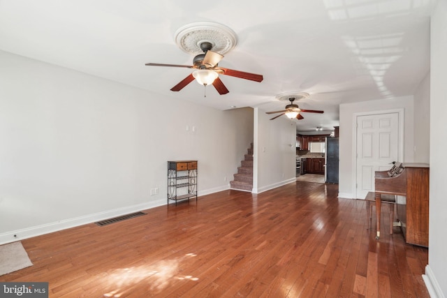 unfurnished living room featuring dark wood-type flooring and ceiling fan