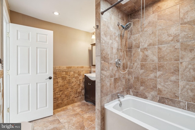 bathroom with tile walls, vanity, and tiled shower / bath