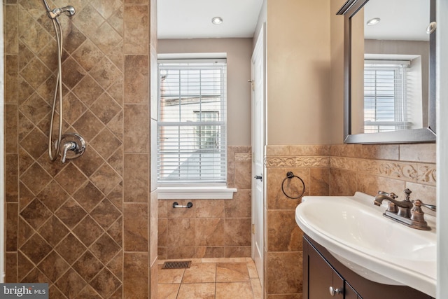 bathroom featuring plenty of natural light, tile walls, and a tile shower