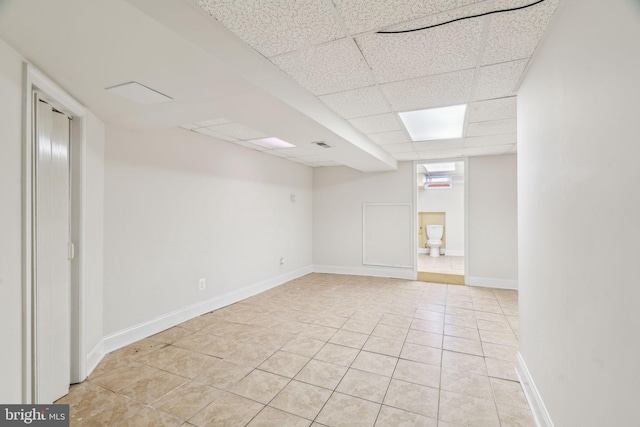 tiled spare room featuring a drop ceiling