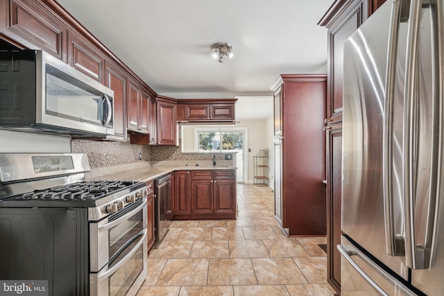 kitchen with tasteful backsplash, appliances with stainless steel finishes, sink, and light tile patterned floors