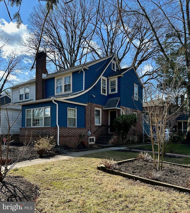 traditional-style home with a front yard, brick siding, and a chimney