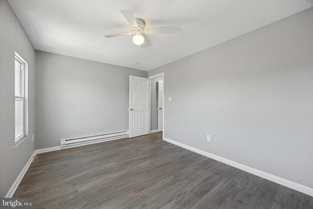 empty room featuring a baseboard radiator, dark wood-type flooring, and a healthy amount of sunlight