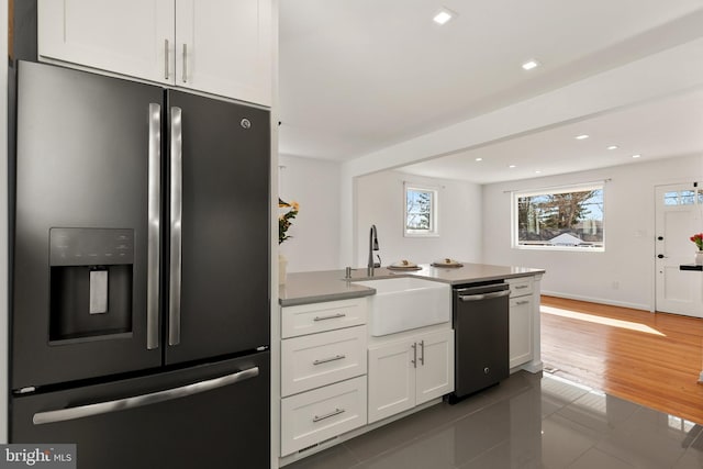 kitchen with appliances with stainless steel finishes, sink, white cabinets, and dark tile patterned flooring