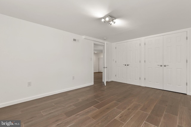 unfurnished bedroom featuring dark hardwood / wood-style flooring and two closets