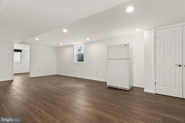 basement with white refrigerator and dark hardwood / wood-style flooring