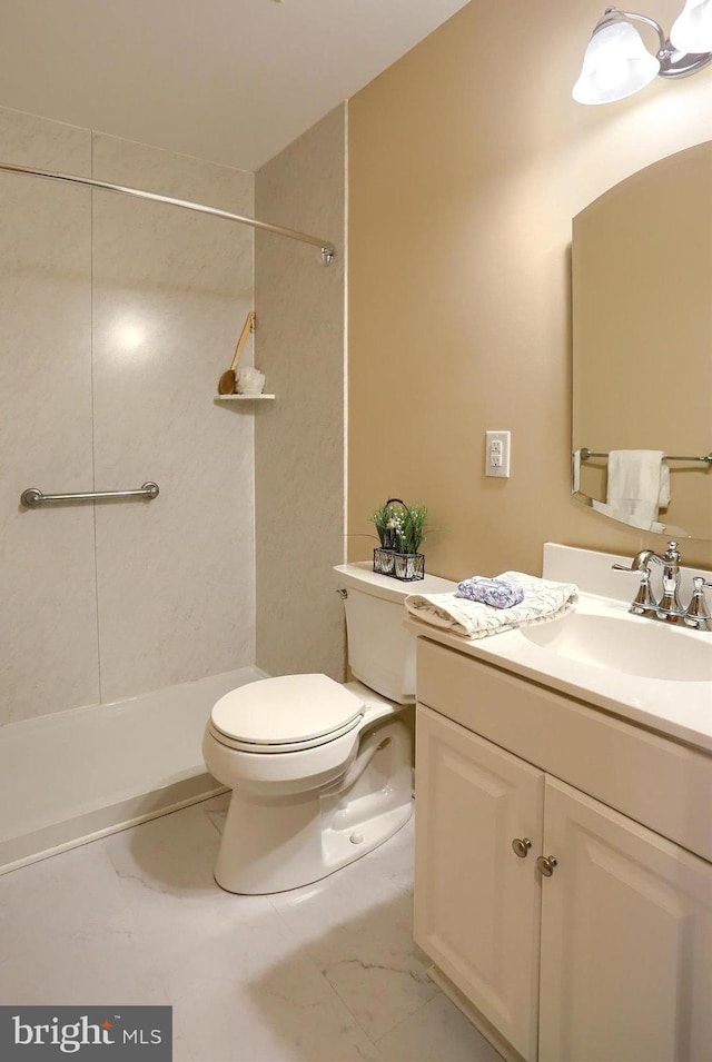 bathroom with a tile shower, vanity, and toilet