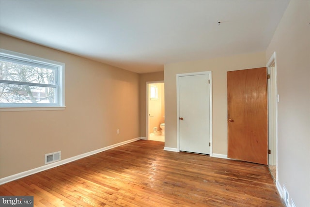 unfurnished bedroom with hardwood / wood-style flooring and ensuite bath