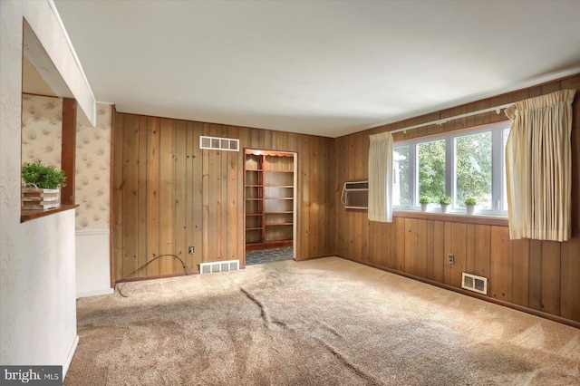 carpeted empty room with wooden walls and an AC wall unit