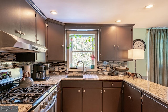 kitchen with stainless steel gas range oven, dark brown cabinets, sink, and backsplash