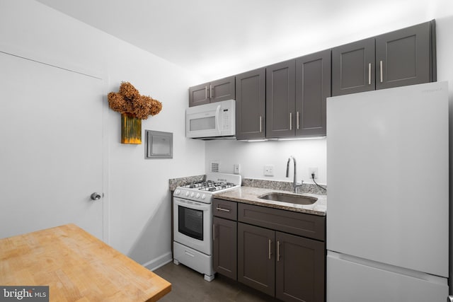 kitchen with light stone counters, sink, and white appliances