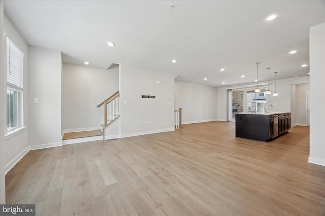 unfurnished living room with sink and light hardwood / wood-style floors