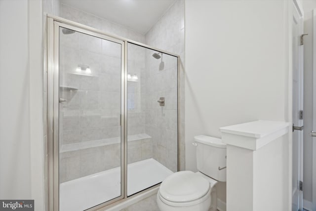 bathroom featuring a shower with shower door and toilet