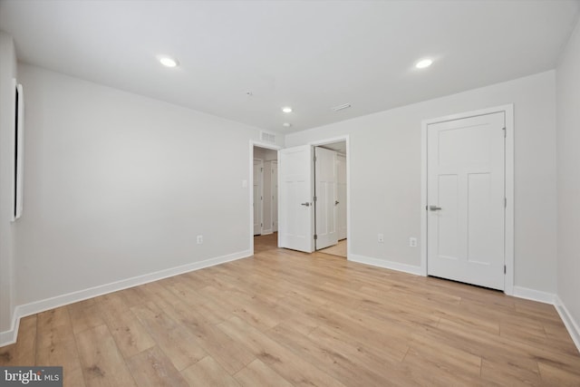 unfurnished bedroom with a spacious closet and light wood-type flooring