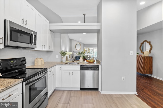 kitchen with white cabinetry, appliances with stainless steel finishes, sink, and light stone counters