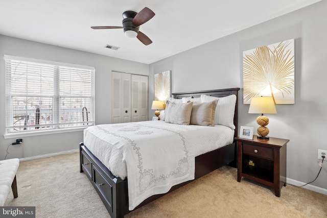 bedroom featuring light carpet, ceiling fan, and a closet