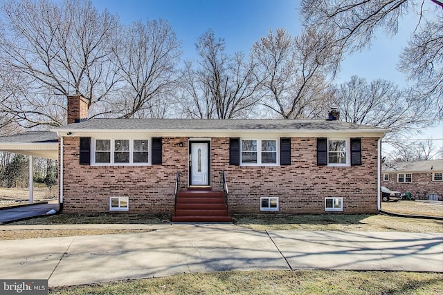 view of front facade with brick siding, an attached carport, driveway, and a chimney