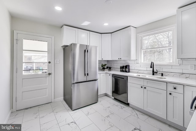 kitchen with dishwashing machine, freestanding refrigerator, a sink, decorative backsplash, and marble finish floor