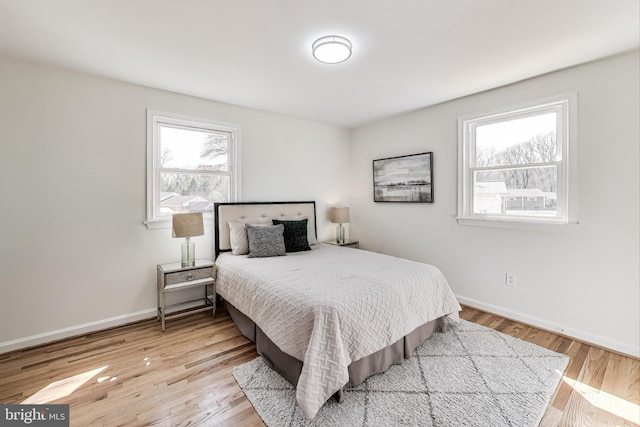 bedroom featuring multiple windows, wood finished floors, and baseboards