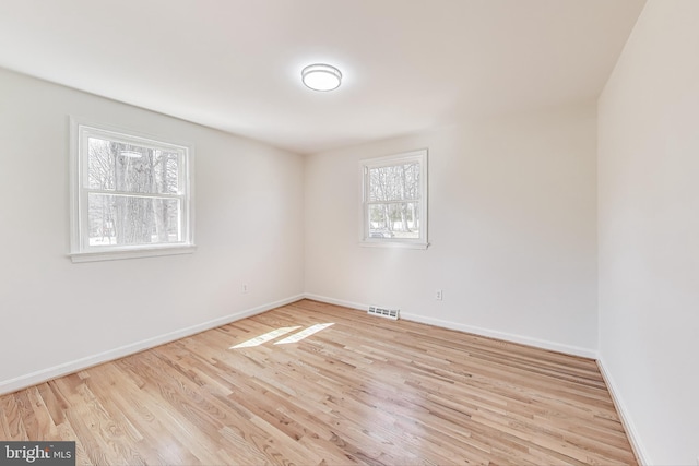 empty room featuring visible vents, baseboards, and wood finished floors