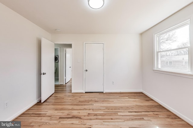 unfurnished bedroom with baseboards and light wood-type flooring